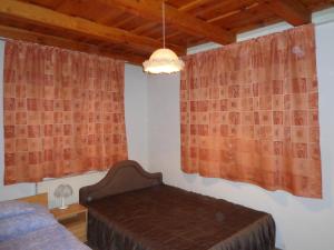 1 dormitorio con cama, cortinas y lámpara de araña en Sóstó Gold Vendégház, en Nyíregyháza