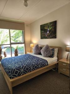 a bedroom with a bed with a blue comforter and pillows at Russell Falls Holiday Cottages in National Park