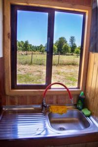 a kitchen sink with a window above it with a view of a field at Angel Cabaña in Villarrica