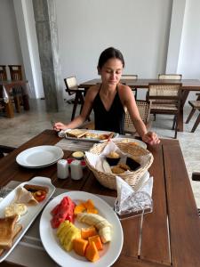 a woman sitting at a table with plates of food at Ami Mirissa in Mirissa