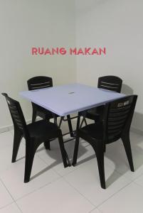 a table with four chairs in a room at Cikgu Huda Homestay Bajet in Seri Manjung