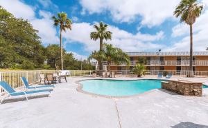 a pool with chairs and tables and a building at Americas Best Value Inn Beeville in Beeville