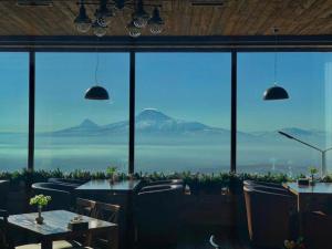 een restaurant met tafels en stoelen en uitzicht op de oceaan bij Amberd Hotel in Byurakan