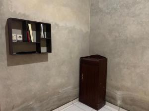 a corner of a room with a book shelf and a cabinet at Aren Homestay in Giripurno