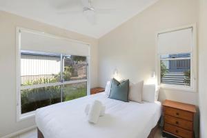 a bedroom with a white bed and two large windows at Reflections Bonny Hills - Holiday Park in Lake Cathie