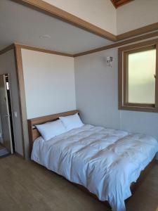 a bedroom with a large white bed with a window at Gyeongpodae Darakbang in Gangneung