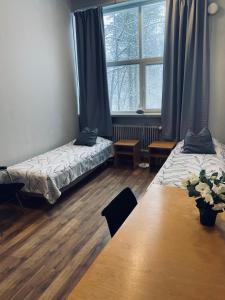 een kamer met twee bedden, een tafel en een raam bij Easy Huoneistot Vierumäki in Härkälä