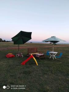 two umbrellas and a picnic table and chairs in a field at "By The Sea" Family apartments in Paralia Dionysiou