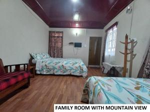 a family room with two beds and a cross on the wall at Odyssey's Pateng Homestay, Cherrapunji in Cherrapunji