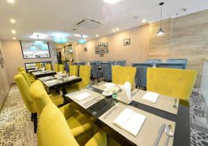 a restaurant with yellow chairs and a long table at Hanoi Emerald Waters Hotel Valley in Hanoi