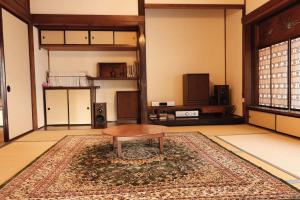 a living room with a table and a rug at Guesthouse SHIGI in Nakatsugawa