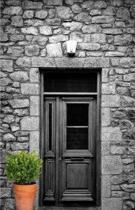 eine Holztür in einem Steingebäude mit einer Pflanze in der Unterkunft Anastasia's Suites Arcadia in Vitina
