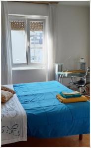 a bedroom with a blue bed with a desk and window at STANZA ORO bagno con doccia idromassaggio in Udine