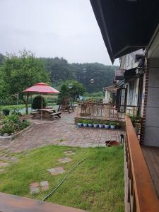 a patio with a picnic table and an umbrella at Gyeongpodae Darakbang in Gangneung