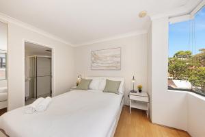 a white bedroom with a large bed and a window at Spacious & Cosy 2 Bedroom Apartment in Darling Harbour in Sydney