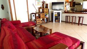 sala de estar con sofá rojo y mesa en La Maison Du Voyage, en Tevaitoa