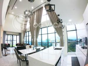 una sala de estar con mesas, sillas y ventanas grandes. en Lovely 3-bedrooms with Karaoke Genting Penthouse en Genting Highlands