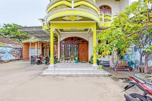 un edificio blanco y amarillo con puerta de madera en SPOT ON 92188 Ndalem Eyang Guesthouse Syariah, en Demak