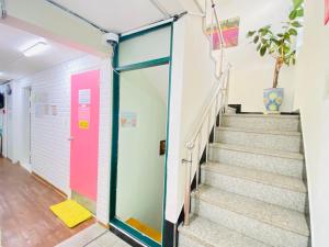 a hallway with stairs and a pink door at Aroha Guesthouse Seoul Station in Seoul +49 photos