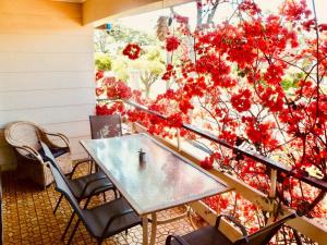 una mesa y sillas en un balcón con flores rojas en Wren's Nest at Culburra Beach, en Culburra Beach