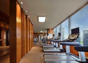 a row of exercise machines in a gym with windows at Sanding New Century Grand Hotel Yiwu in Yiwu