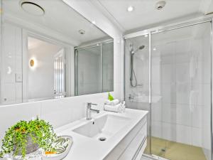 La salle de bains blanche est pourvue d'un lavabo et d'une douche. dans l'établissement urban oasis in the heart of town, à Port Douglas