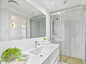 y baño blanco con lavabo y ducha. en urban oasis in the heart of town en Port Douglas