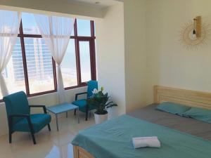 1 dormitorio con 1 cama, 2 sillas y ventanas en Căn hộ Sơn Thịnh - Homestay, en Vung Tau