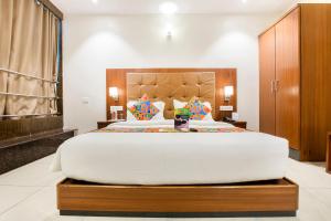 a large bedroom with a large white bed with a wooden headboard at FabHotel Prime Le Western in Mumbai