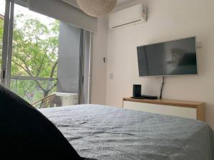 1 dormitorio con 1 cama y TV de pantalla plana en Excelente depto. en Almagro con Balcón a la calle en Buenos Aires