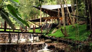 a wooden building with a staircase next to a waterfall at Voraman B-One in Chiang Mai