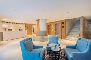 a lobby with blue chairs and a staircase at Citrus Sukhumvit 11 by Compass Hospitality in Bangkok