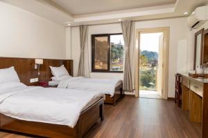 Habitación de hotel con 2 camas y ventana en YULOKO GUEST HOUSE en Katmandú
