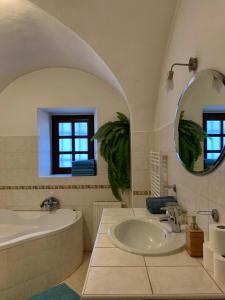 een badkamer met een bad, een wastafel en een spiegel bij VIP MiKU apartman 2 in Mikulov
