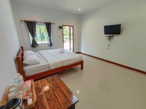 a bedroom with a bed and a table and a television at ปาลินรีสอร์ท in Chiang Khan
