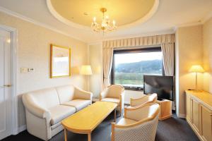 a living room with a couch and a tv at Hotel City Plaza Kitakami in Kitakami