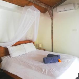 a bedroom with a white bed with a white canopy at The Joglo Kedungu, Traditional Teakwood in Tanah Lot