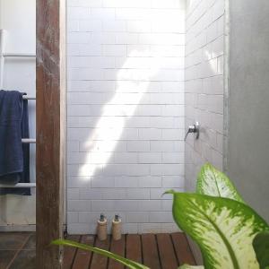 a bathroom with a white tiled shower with a plant at The Joglo Kedungu, Traditional Teakwood in Tanah Lot