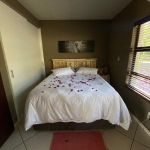 um quarto com uma cama branca com flores vermelhas em Glenvista Home with a View em Joanesburgo