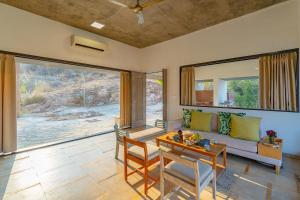 a living room with a couch and a table at StayVista's Sage Scenery - Mountain-View Villa with Infinity Pool & Terrace in Udaipur