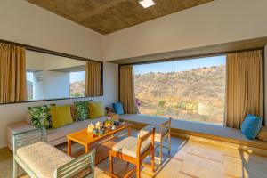 a living room with a couch and a table at StayVista's Sage Scenery - Mountain-View Villa with Infinity Pool & Terrace in Udaipur