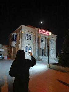 una persona che scatta una foto di un edificio di notte di ضيافة الأمير The Prince Hospitality a Barka