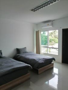 two beds in a bedroom with a window at Baan7984 Rawai in Rawai Beach