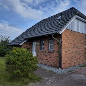 una casa de ladrillo rojo con techo negro en Ferienhaus Helmsand 2, en Friedrichskoog