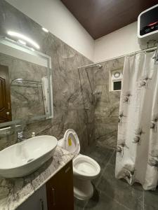 a bathroom with a sink and a toilet and a shower at Orchard Valley View Home Stay in Ooty