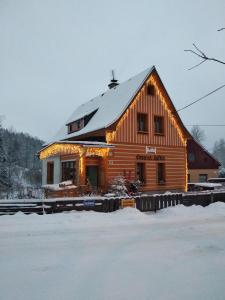 a large wooden house with a snow covered roof at Apartmány Černá Říčka in Desná
