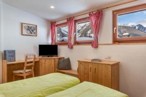 een slaapkamer met 2 bedden en een bureau met een televisie bij Mountainfarm Innertrein Wald in Cadipietra