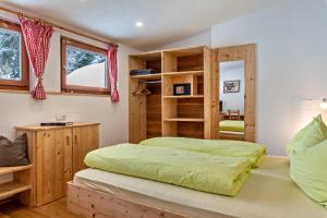 a bedroom with a green bed and wooden shelves at Mountainfarm Innertrein Wald in Cadipietra