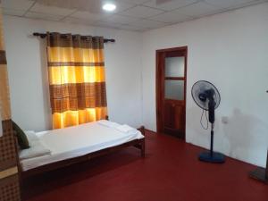 een kamer met een bed, een ventilator en een raam bij sinhagiri hotel & restaurant in Tangalle