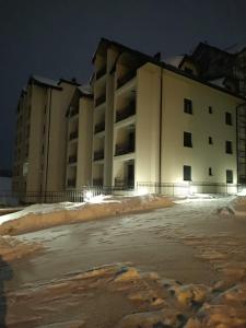 un edificio de apartamentos en la nieve por la noche en Apartman Relja Zlatibor, en Zlatibor